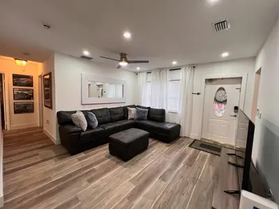 a living room with a black leather couch and stool at Welcome to Miami Springs Charm in Miami