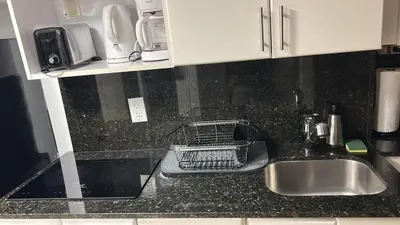 a kitchen counter with a sink and a dish drying rack at Apartment View to the Beach Sunny Isles in Sunny Isles Beach