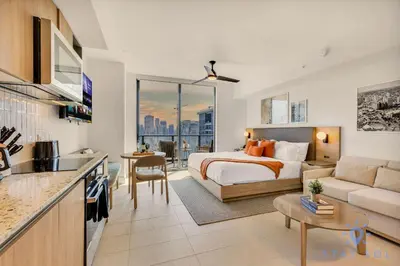a bedroom with a bed and a kitchen with a couch at Lovely Studio - Pool & Gym in Miami