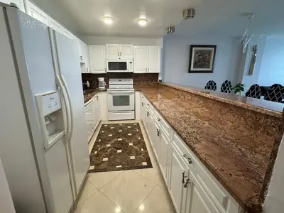 a kitchen with white cabinets and a refrigerator at Luxury Ocean Reserve Condo Pool, Gym & Beach Access in Sunny Isles Beach