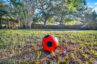 a red and black soccer ball sitting on the grass at HUGE Outdoor soccer 4BR HEATED Pool house near Las Olas in Fort Lauderdale