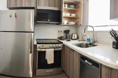 a kitchen with a stainless steel refrigerator and a sink at Charming DBL W pool and parking 15 min to FLL and Beach in Hollywood