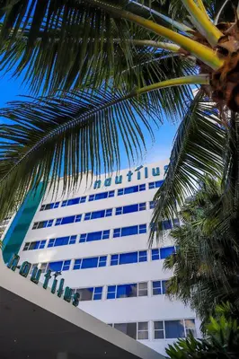 a hotel building with a palm tree in front of it at Nautilus Sonesta Miami Beach in Miami Beach