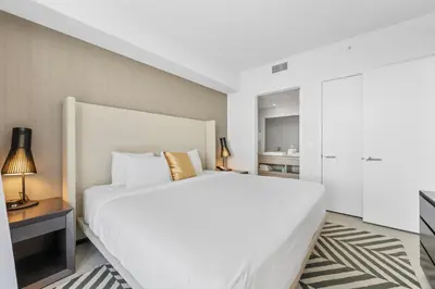 a bedroom with a large white bed and a table at Stunning High-Floor City View 1BR Hyde Beach House in Hollywood