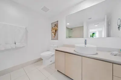 a white bathroom with a sink and a toilet at 1 Bedroom & Kitchen at Beachwalk Luxe Pool - Gym in Hallandale Beach