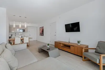 a living room with a couch and a tv and a kitchen at 1 Bedroom & Kitchen at Beachwalk Luxe Pool - Gym in Hallandale Beach