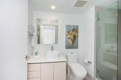 a white bathroom with a sink and a toilet at Amazing Studio in Beachwalk with Pool and Beach in Hallandale Beach