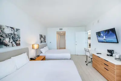a white hotel room with a bed and a desk at Beachwalk 2 Bedrooms & Kitchen in Hallandale Beach