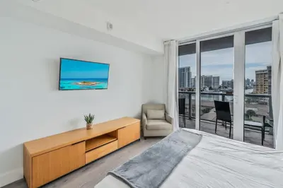 a bedroom with a bed and a desk and a window at 2BR & 2BA Oasis at Beachwalk in Hallandale Beach