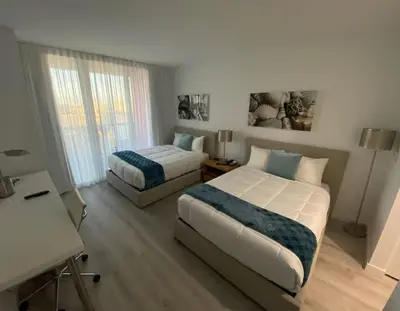 a bedroom with two beds and a desk in it at 2 Bed 2 Bath Full Equiped Beachwalk Pool Gym 22 in Hallandale Beach