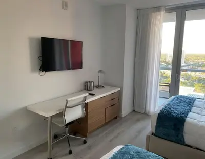 a bedroom with a desk and a bed and a desk with a computer at 2 Bed 2 Bath Full Equiped Beachwalk Pool Gym 22 in Hallandale Beach