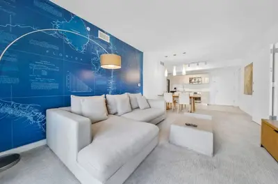 a living room with a white couch and a blue wall at 1 Bed & Kitchen at Beachwalk Luxe Pool Gym Beach in Hallandale Beach