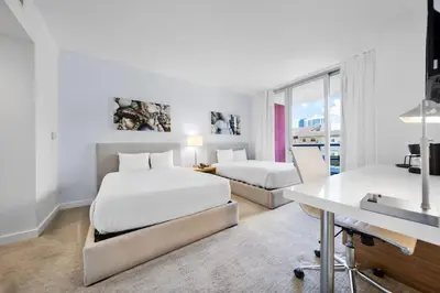 a hotel room with two beds and a desk at 2 Bed & 2 Bath at Beachwalk Pool Gym Beach on 19th in Hallandale Beach