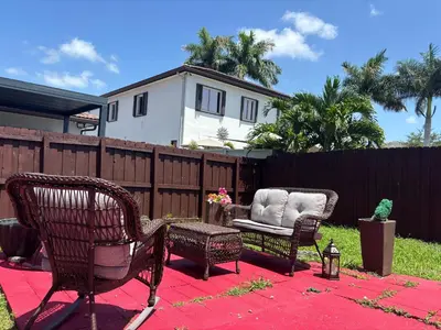 a backyard with two chairs and a bench and a fence at Lujosa Y Acogedora Casa En Miami! in Tamiami