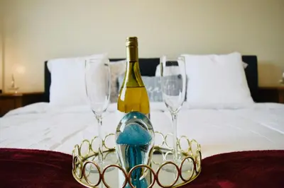 a bottle of wine and two glasses on a bed at Lujosa Y Acogedora Casa En Miami! in Tamiami