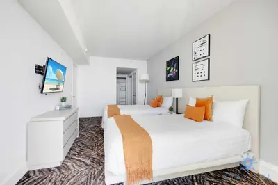 a white bedroom with two beds and orange pillows at Cozy Apartment with Balcony in Hollywood