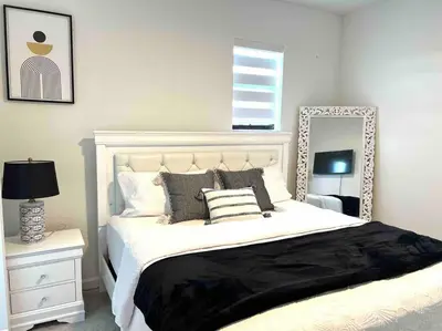a bedroom with a large white bed with a mirror at Cozy house in Goulds