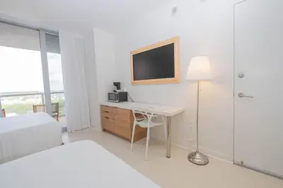 a white bedroom with a desk and a tv at Studio Luxury Ocean Views Apt in Hallandale Beach in Hallandale Beach