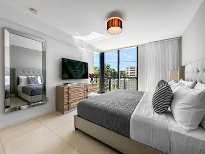 a bedroom with a large bed and a mirror at Bay Breeze Premium Apartments by Eskape Collection in Miami Beach