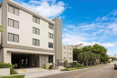 a white building on a street with a car parked in front at Urban Oasis in Miami Close to Bayside and Brickell with Free Parking in Miami