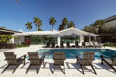a pool with chairs and umbrellas next to a house at Palm Pointe - One third of a mile to the beach - Heated Pool - Intracoastal Views in Fort Lauderdale