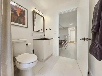 a white bathroom with a toilet and a mirror at Casa Eden - Half mile to Lauderdale Marine Center - 4 bedrooms - 2 bathrooms in Fort Lauderdale