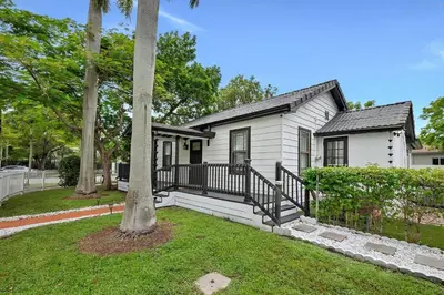a white house with a porch and trees at Casa Del Sol Cozy 2br Retreat 10 Mins To Beach in Miami