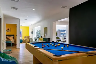 a pool table in a living room with a pool at Stunning 8 bedroom Villa with Pool Basketball Pickleball BBQ Mini-golf and more in North Miami
