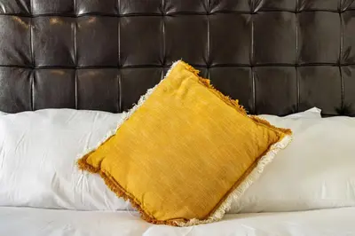 a yellow pillow on a bed with white pillows at Casa Fillmore - Hollywood Oasis in Hollywood