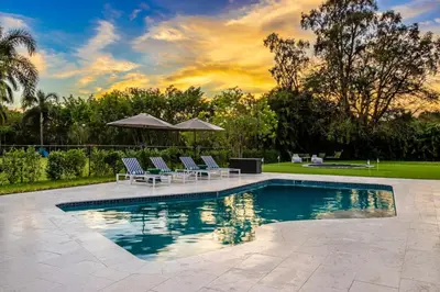 a pool with chairs and umbrellas in a yard at Villa Tation 8BR Mini Hotel in Plantation