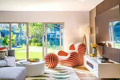 a living room with orange and white chairs in front of a window at Villa Tation 8BR Mini Hotel in Plantation