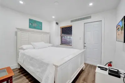 a white bedroom with a white bed and a window at Seaside Beach House in Hollywood