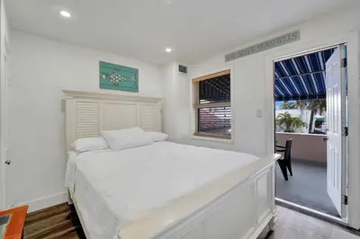 a white bedroom with a bed and a window at Seaside Beach House in Hollywood