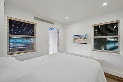 a white bedroom with a bed and two windows at Seaside Beach House in Hollywood