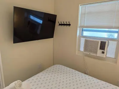 a bedroom with a flat screen tv and a window at Beach Breeze Suite - Steps to the Beach in Hollywood