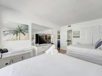 a white bedroom with two beds and a television at Lovely 2BR condo with Resort Access, Gym and Pool 1608 in Miami Beach