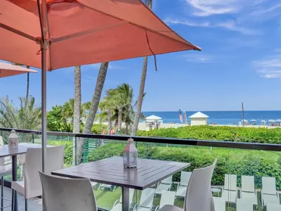 a table and chairs with an umbrella and the beach at Lovely 2BR condo with Resort Access, Gym and Pool 1608 in Miami Beach