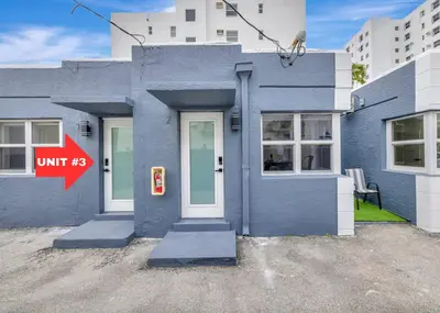 a blue house with a white door and a red sign at Banyan St. Studio off Las Olas- Steps to the Beach in Fort Lauderdale