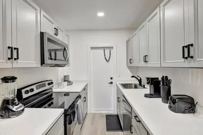 a white kitchen with white cabinets and a sink at Banyan St. Studio off Las Olas- Steps to the Beach in Fort Lauderdale