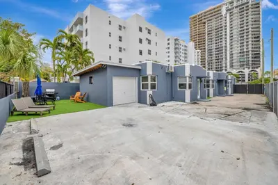 a blue house in a yard with buildings at Banyan St. Studio off Las Olas- Steps to the Beach in Fort Lauderdale