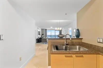 a kitchen with a sink and a living room at Luxurious 2BD Condo with Direct Ocean Front & Resort Pool in Sunny Isles in Sunny Isles Beach