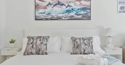 a white bed with two pillows and a painting on the wall at Beachside Studio in Hollywood