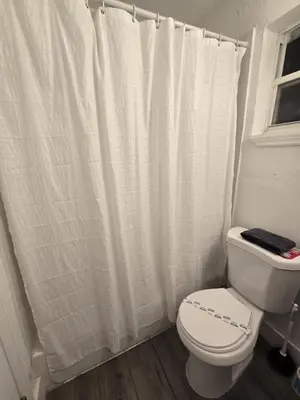 a bathroom with a white shower curtain and a toilet at Cozy Place Near Design District - 3 in Miami