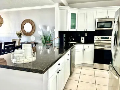 a kitchen with white cabinets and a black counter top at Miami apartamento sobre la playa con estacionamiento gratuito in Miami Beach