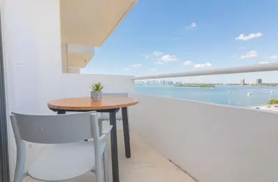 a table and chair on a balcony with a view of the water at North Bay in Miami Beach