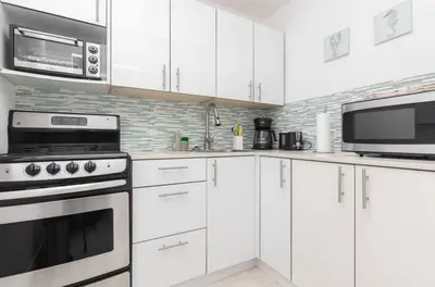 a white kitchen with white cabinets and a microwave at North Bay in Miami Beach