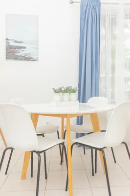 a white dining room table and chairs with a blue curtain at Ocean Villa in Miami Beach