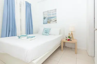 a bedroom with a white bed with blue curtains and a table at Ocean Villa in Miami Beach