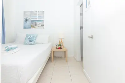 a white bedroom with a bed and a table at Ocean Villa in Miami Beach