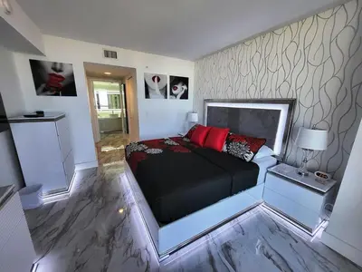a bedroom with a bed with black sheets and red pillows at The Royal Suite of Beachwalk 2b 2b Apmt in Hallandale Beach